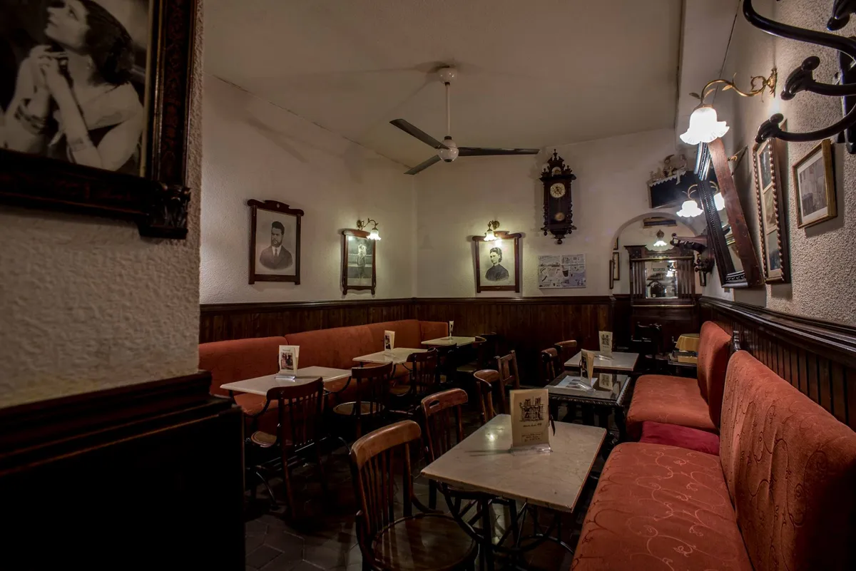 Cozy interior of a traditional cafe in Madrid with marble tables, velvet red benches, and vintage portraits, providing a quiet atmosphere for those seeking productive study spots in Madrid.