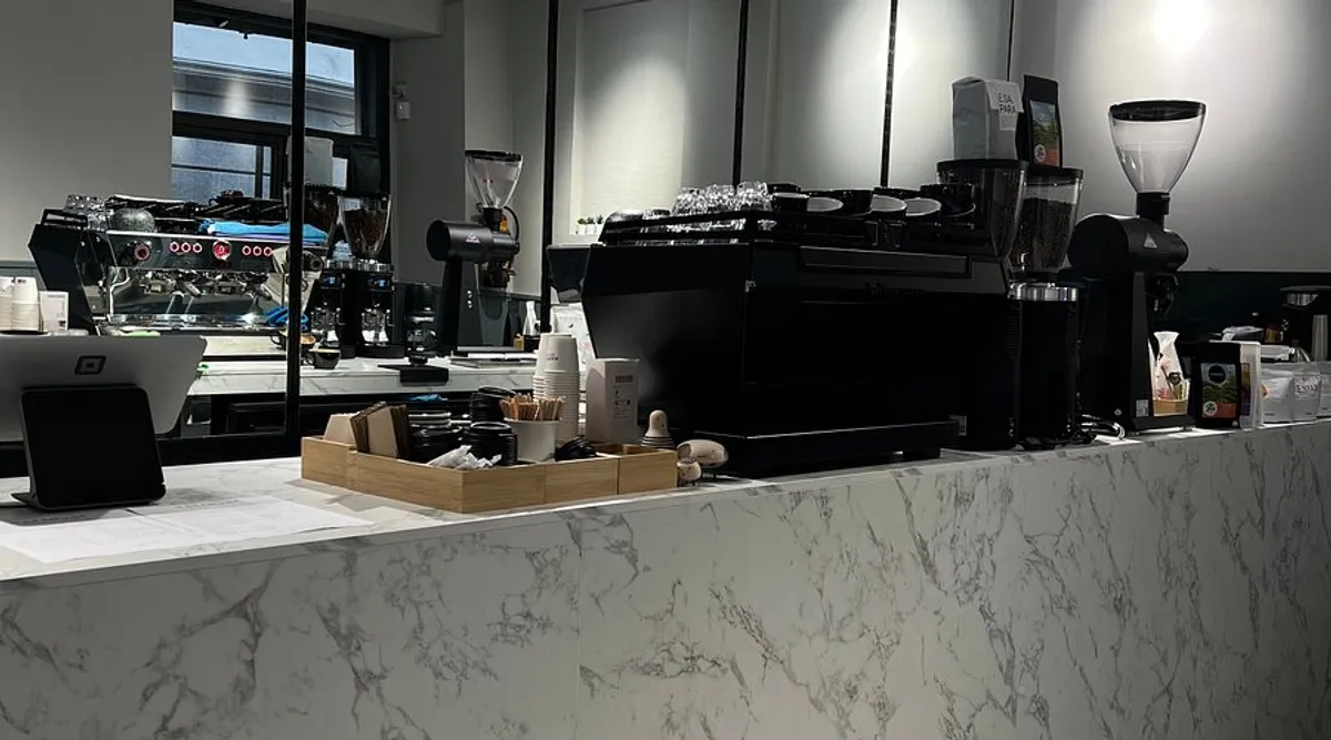 Focused interior of Masamune Specialty Coffee Madrid with long wooden tables and warm pendant lighting; a quiet and laptop-friendly environment designated as one of the best weekday study spots in Madrid.