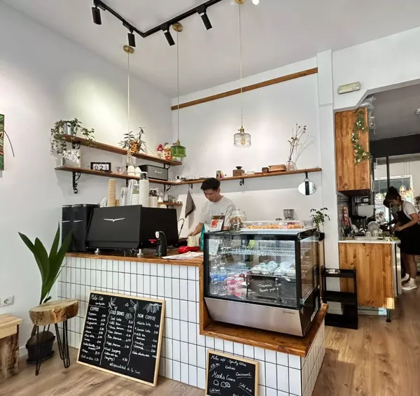 The bright, modern coffee bar at Miles Café, a cozy specialty cafe in Madrid located near Lavapiés square, featuring white tile walls, a professional espresso machine, and a focused environment perfect for quiet study spots in Madrid.