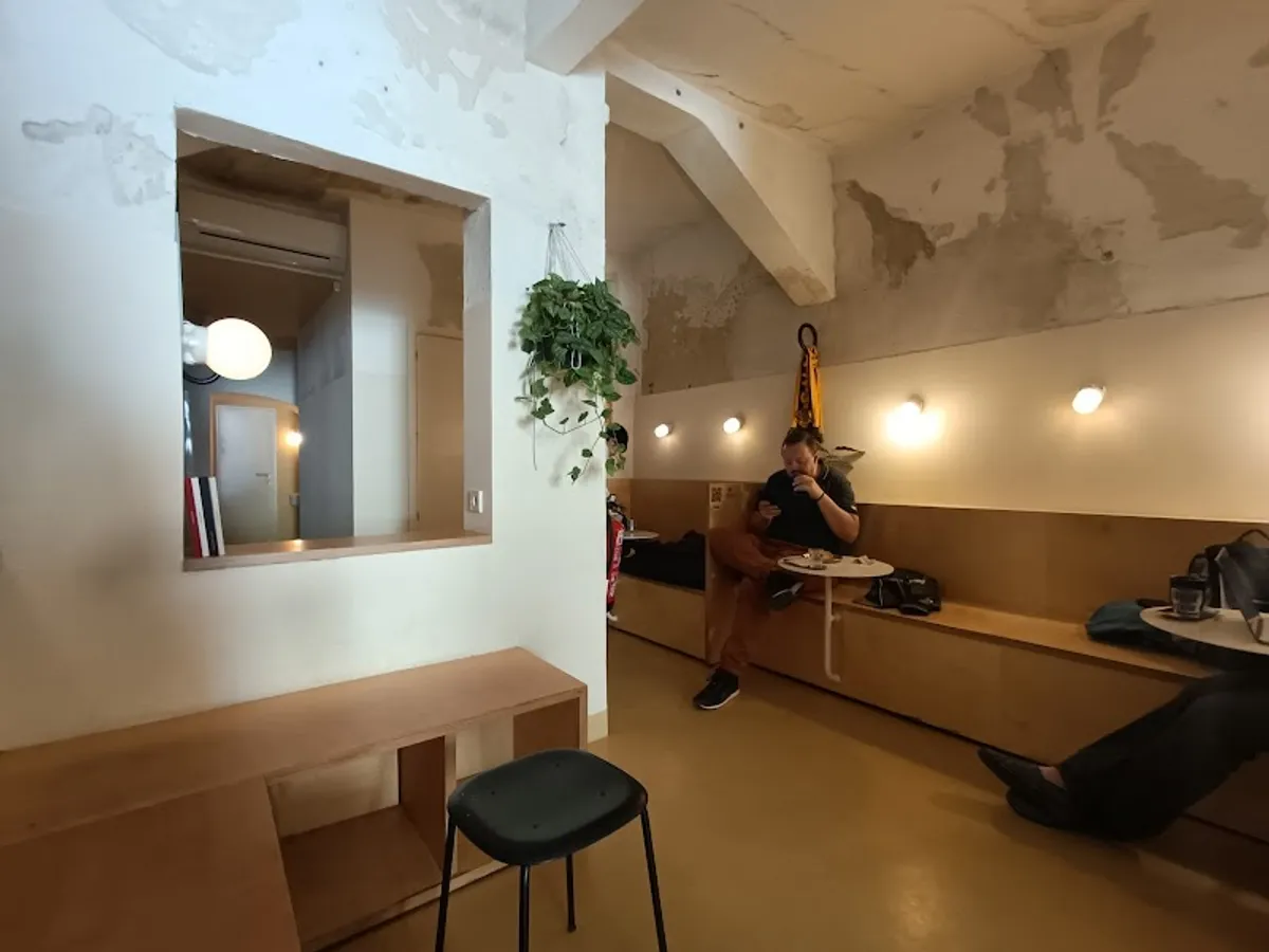 Minimalist seating area at Hola Coffee Madrid featuring light wood benches and warm spotlighting, creating a focused and serene environment ideal for productive study spots in Madrid.