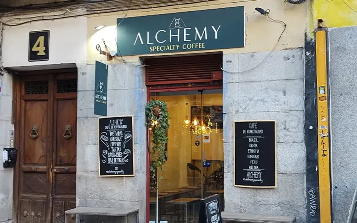Street view of Alchemy Specialty Coffee in Madrid, a contemporary specialty cafe Madrid with chalkboard menus and a glass storefront, popular for its high-quality beans and work-friendly atmosphere.