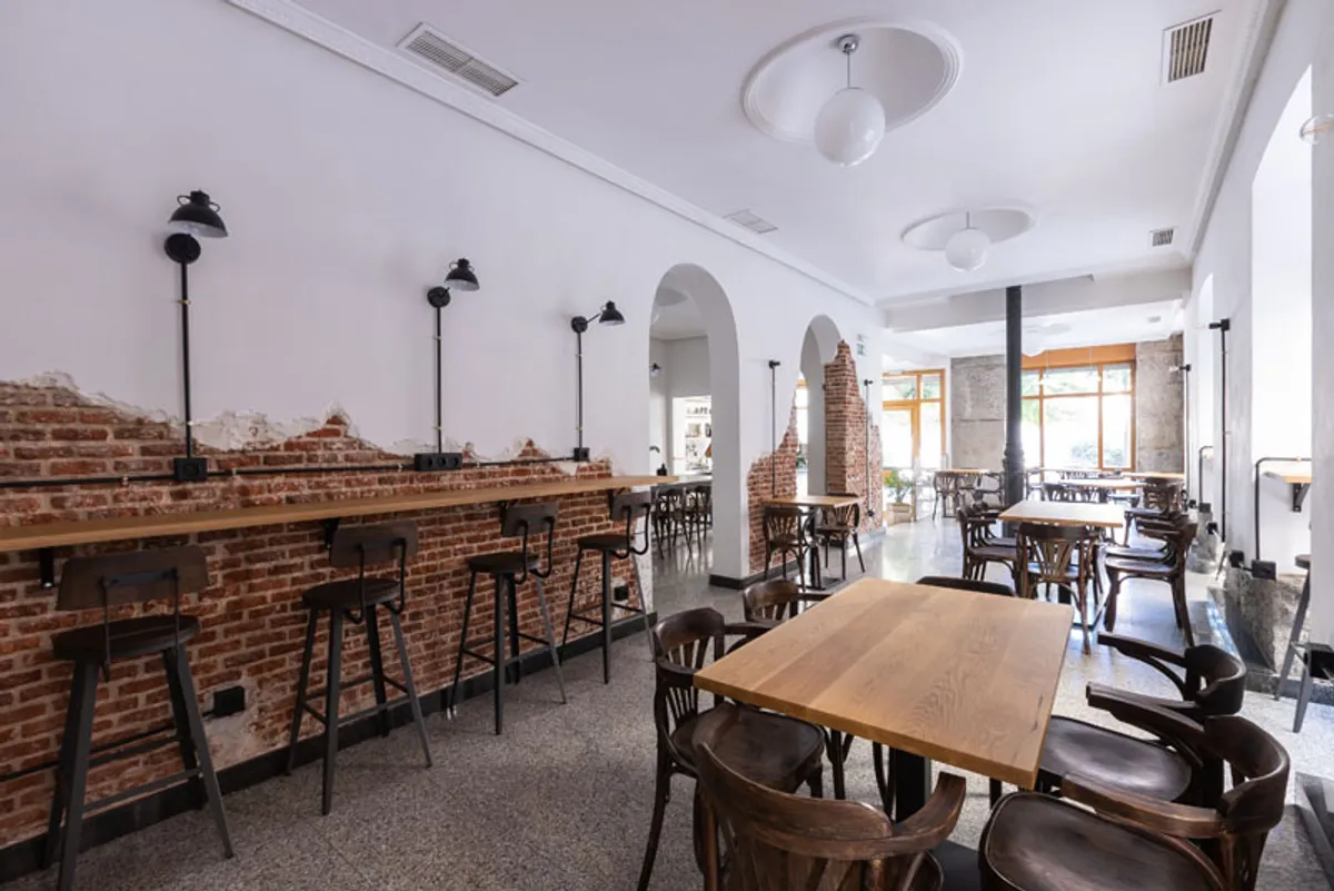 Spacious industrial interior of Four Specialty Coffee Madrid featuring exposed brick walls, long wooden workbars with power outlets, and ample seating—designed as one of the most productive study spots in Madrid for remote workers.