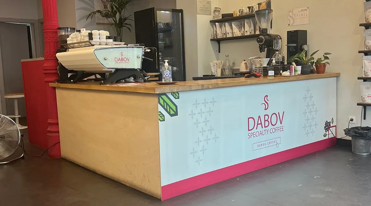 The modern service counter at Dabov Specialty Coffee Madrid featuring a professional espresso machine, wood-topped bar, and clean minimalist design, providing a focused environment for one of the premier study spots in Madrid.