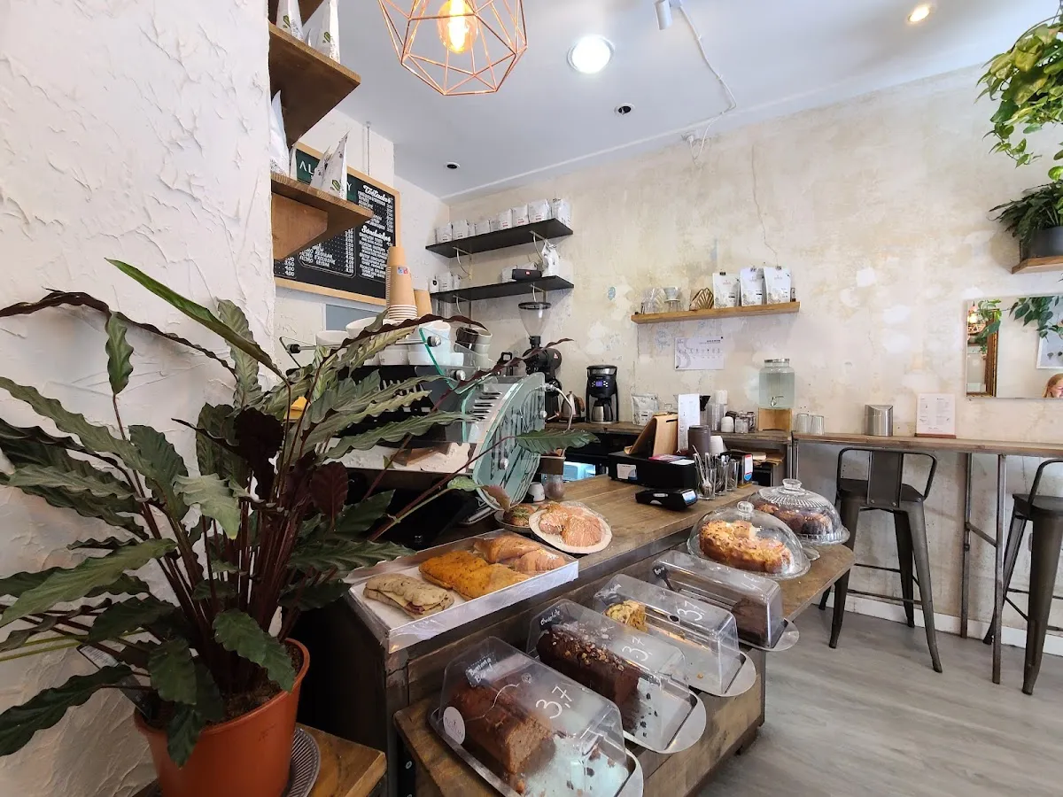Modern interior of Alchemy Specialty Coffee, a minimalist cafe in Madrid featuring a wooden pastry counter, laptop-friendly bar seating, and bright lighting ideal for productive study spots in Madrid.