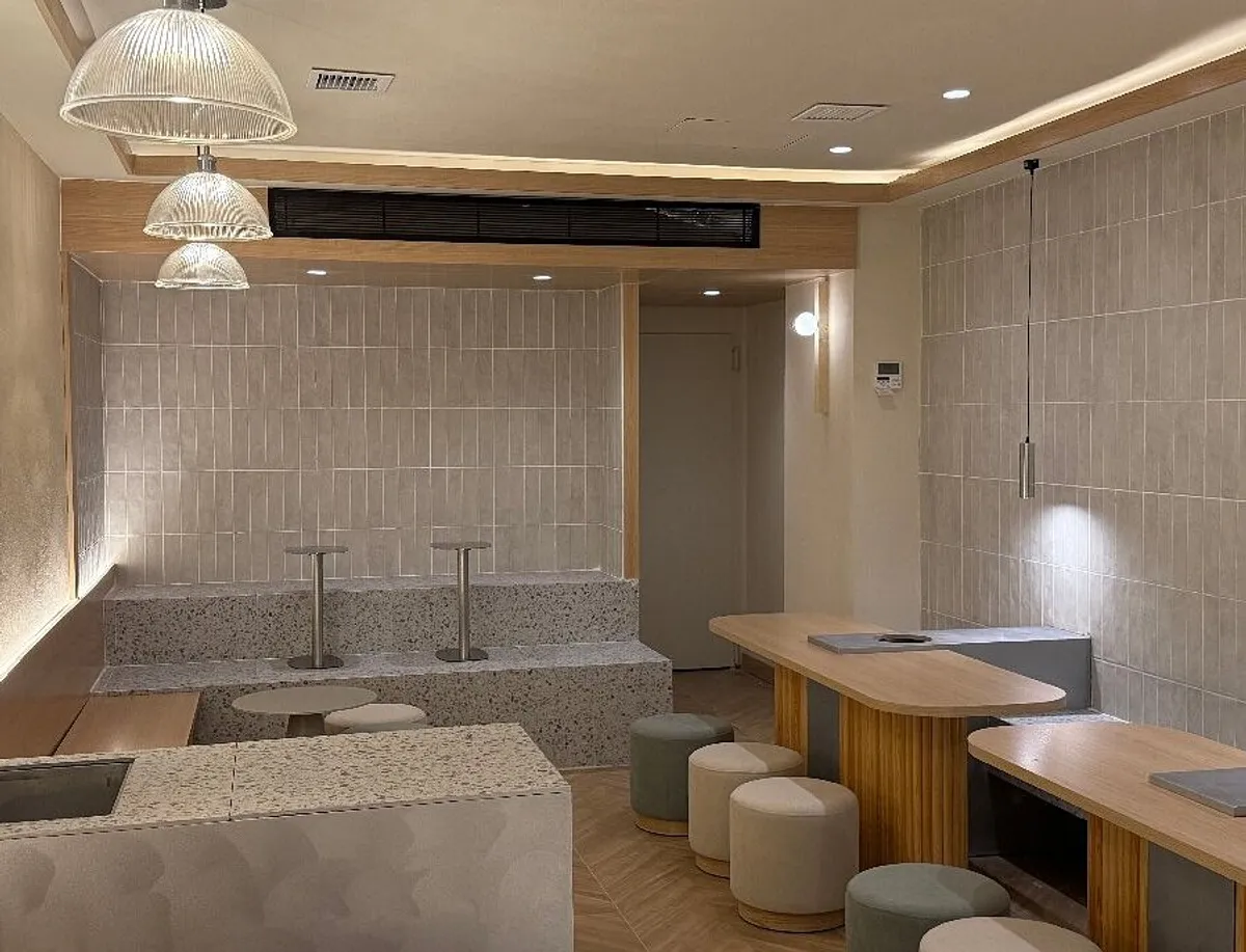 Minimalist interior of Despacito Coffee, a modern cafe in Madrid with sleek gray tile walls, terrazzo benches, and wooden tables—a quiet and bright environment for those looking for productive study spots in Madrid.